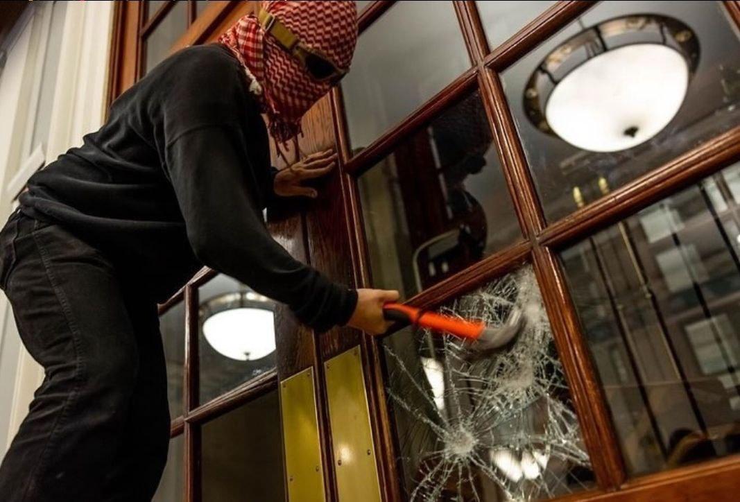 A student occupier uses a hammer to smash a window pane during the occupation of Hind's Hall at Columbia University.