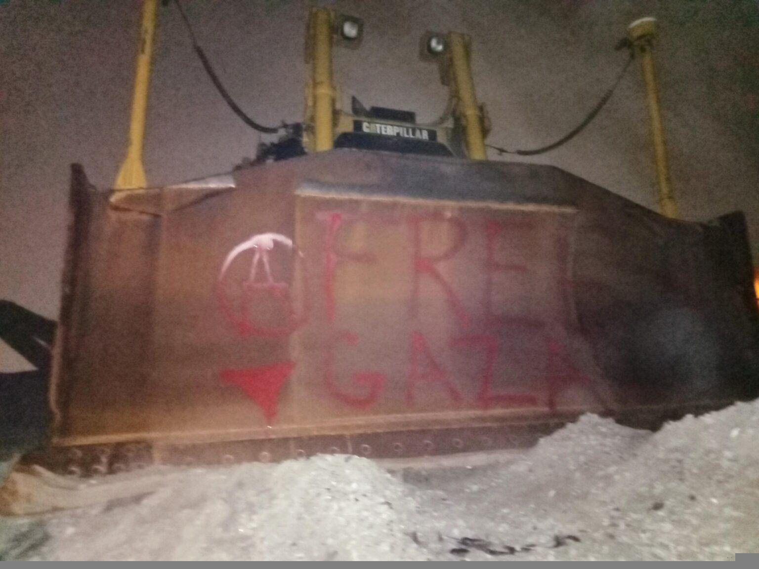 A vandalized CAT machine. Graffiti reads "FREE GAZA". There is also a circle-A and a red downward triangle.